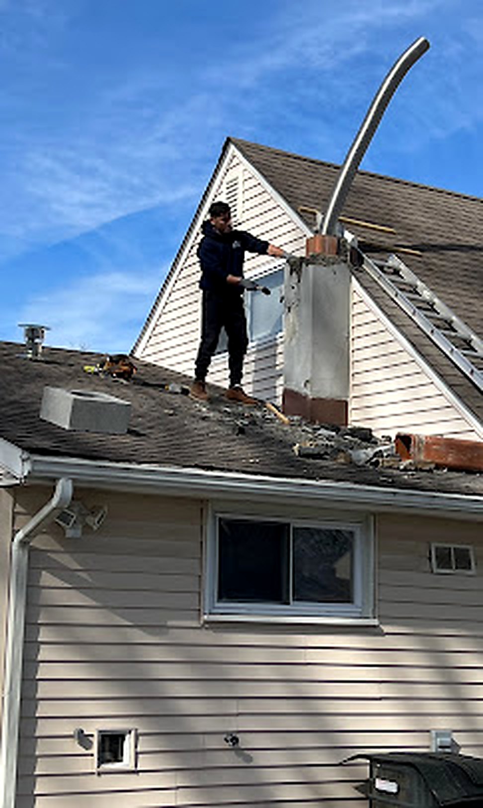 Worker installing new flashing at brick chimney base